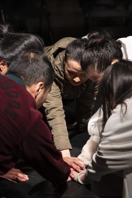 多人俯身围拢，手部聚集在中间