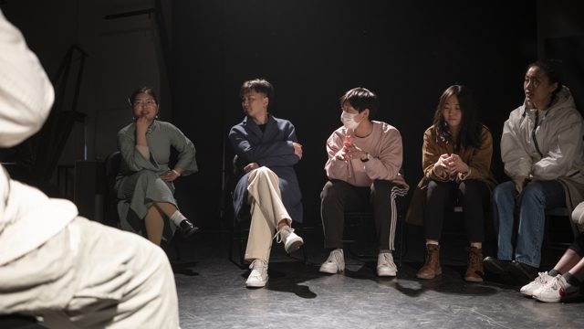 数人坐成弧形，前景有人物局部