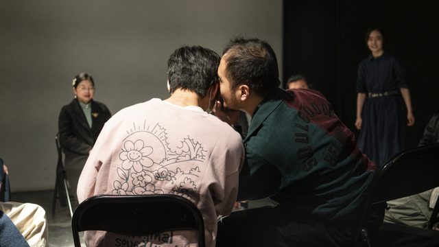 两人近距离侧身，旁人围坐观看