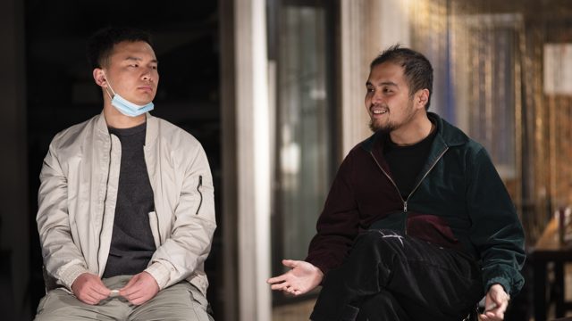 两人坐姿，右侧人物摊开手掌