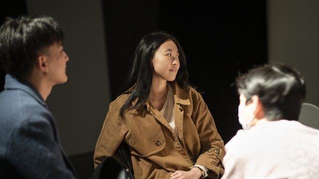 三人相向，中央人物张口说话姿态