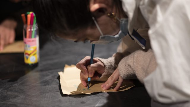 纸、彩色笔及持笔书写的手部近景