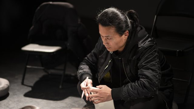 一人坐姿前倾，手里握着物件