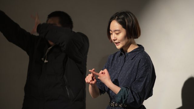一人站立手部在胸前，后方另一人举臂
