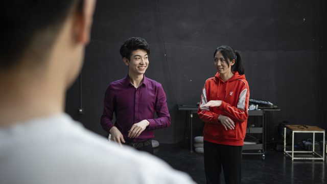 两人并排站立，近处另一人背影