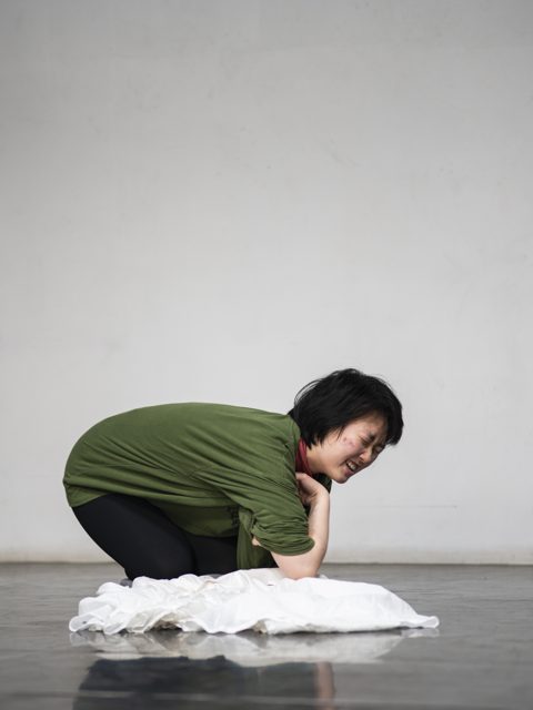 一人蹲在地面白色织物旁