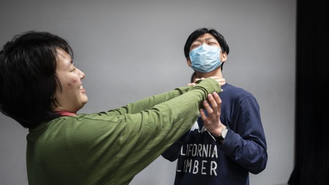 两人相向，一人手接近另一人肩颈