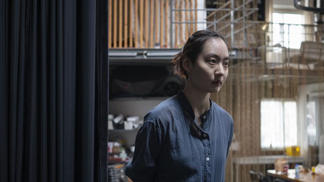 人物近景，后方可见楼梯和空间结构