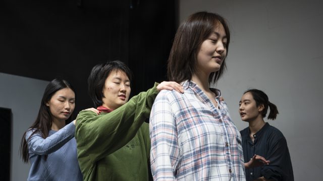 三人前后排成一列，手部落在前人的肩部